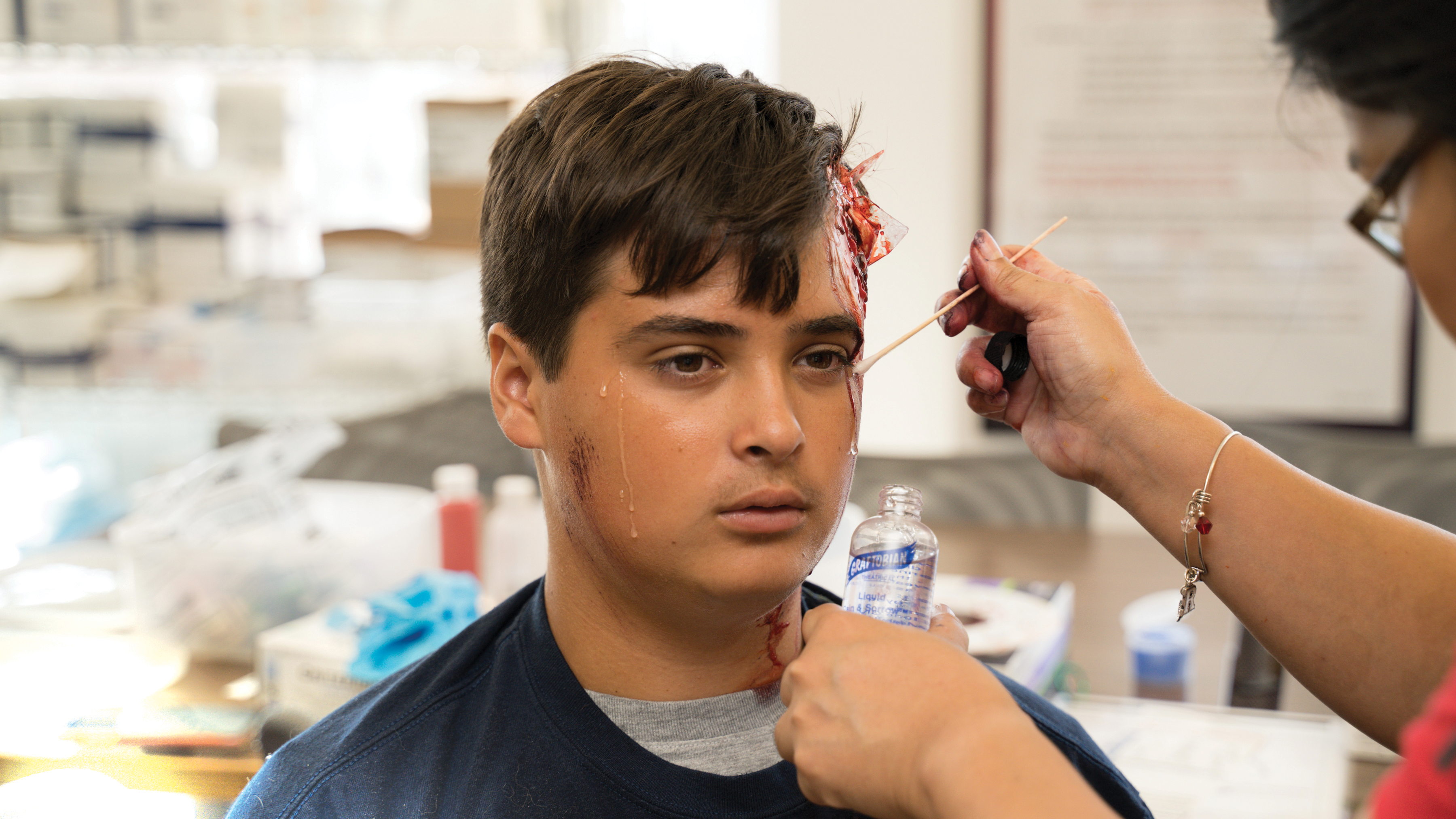 Viray applies makeup to volunteer Gus Filippelli during a disaster nursing simulation.