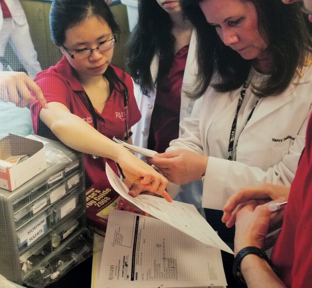 Students Working with the clinical lab instructor, pointing to documents.