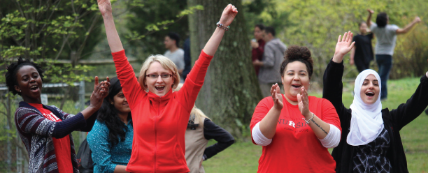A group of 4 nursing students at Rutgers Gardens cheering on their classmates during a game at the School Picnic
